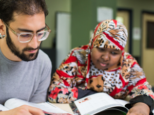 Tutor and student sitting together and looking at books